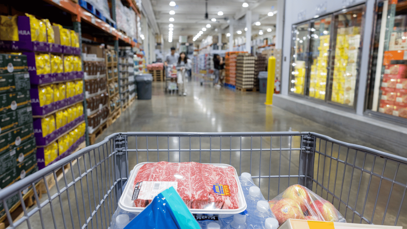 A shopping cart full of products in a warehouse club store.